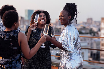 Dark-skinned girl pours champagne into glasses of her multinational friends