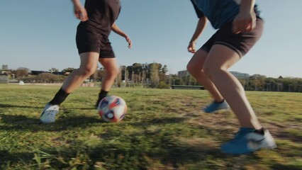 Two young female athletes playing soccer on an outdoor field on summer day, running and dribbling a ball during a game. Handheld camera, close-up shot - Powered by Adobe