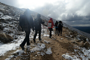 Hiking people in a mountainous area walk along a path