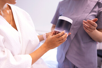 Smiling blonde woman in white coat with paper catalog in her hands consults with her beautician