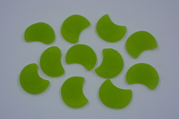 Bright and high-quality children's gummy candies in the form of a green moon, talismans located on a white background.
