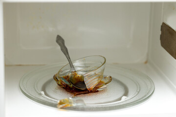 A cup that burst in the microwave while heating honey and a steel spoon forgotten in it