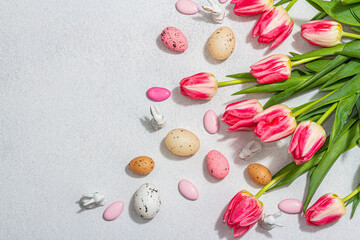 Pink tulips with Easter eggs on light stone concrete background. Festive concept, greeting card