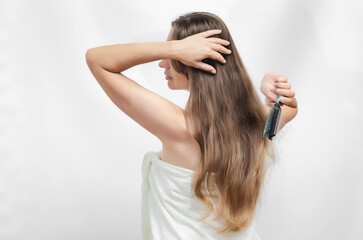 Fototapeta premium Woman combs her hair after bath. Woman in White Towel