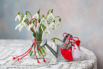 Snowdrop flowers on the table in a vase, watering can, red and white symbol of Martenitsa holiday Martisor, Baba Martha, still life, postcard