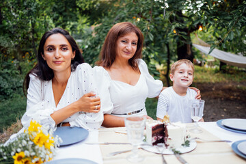 Little boy, his mother and grandmother are sitting at a festive table. Happy family celebrates birthday.