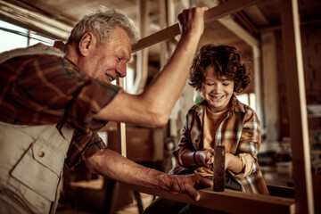 Obraz na płótnie Canvas Grandfather Teaching Woodworking to His Grandson