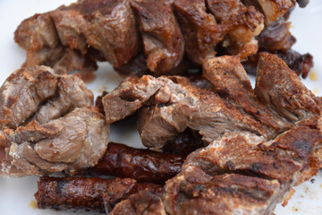 Roasted steak and sausages on a plate close up, well done steak