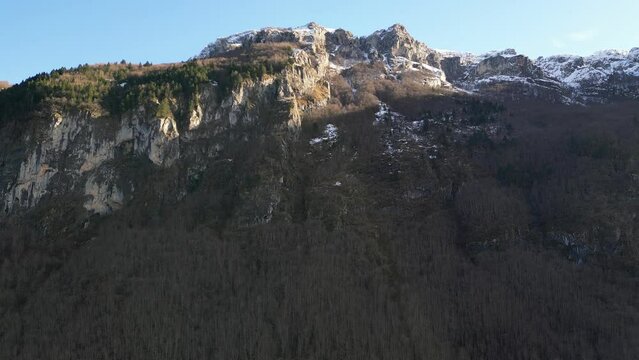 The drone flies up to a huge, relief mountain with a snow-capped peak