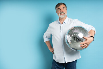 Photo of positive old man hold disco ball isolated on blue background.