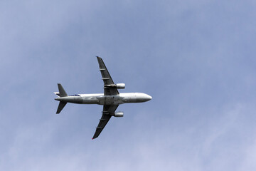 A jet plane flying in a blue sky between clouds. Transportation. Air travel. Trip