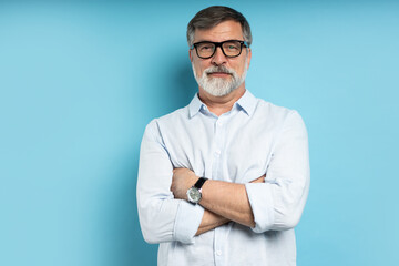 Bearded middle-aged man wearing glasses posing over blue studio background