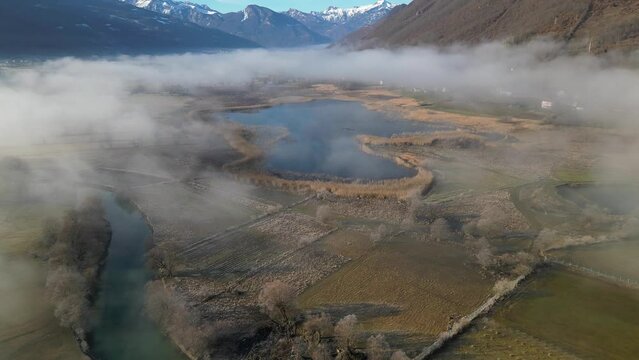 The drone flies over lakes and rivers covered in fog, surrounded by mountains