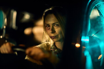 Woman with bruises from domestic violence driving a car at night