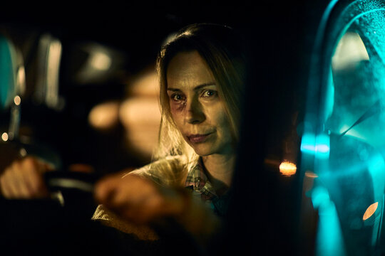 Woman with bruises from domestic violence driving a car at night