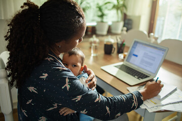Working mother multitasking with baby at home office