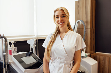 Portrait of Blond female beautician using massager in salon.