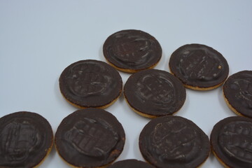 Delicious round sponge cake biscuits with natural jam that are covered with natural chocolate placed on a white background.