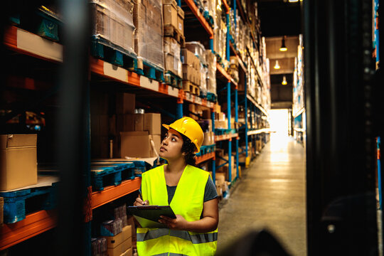 Female warehouse worker checking inventory in industrial storage area