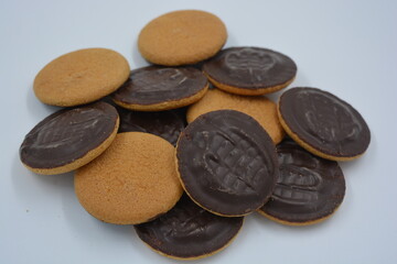 Delicious round sponge cake biscuits with natural jam that are covered with natural chocolate placed on a white background.