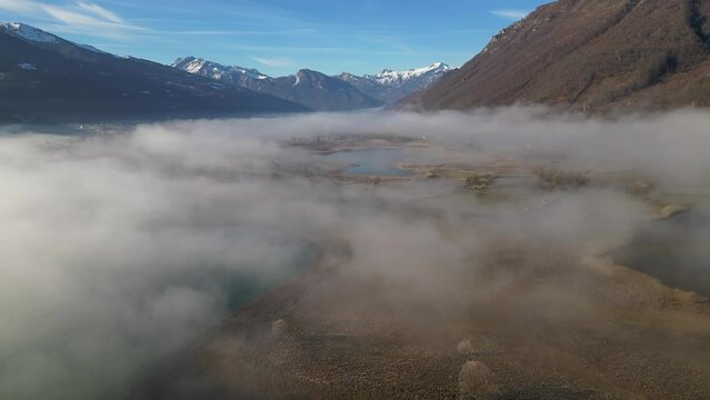 The drone flies over lakes and rivers covered in fog, surrounded by mountains