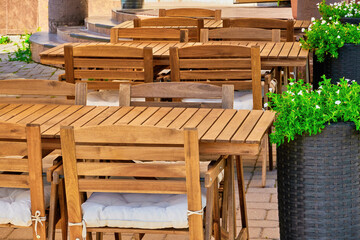 wooden furniture, tables and chairs of a cozy outdoor cafe on a clear sunny summer day. beautiful...