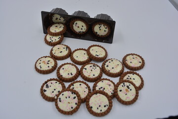 Delicious branded, factory-made, chocolate chip cookies with white fudge, fruit, chocolate pieces arranged on a white background. Biscuits are in a brown, pretty package.