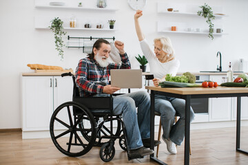 Happy Caucasian couple, pretty wife and bearded man in wheelchair, pay for food with credit card...