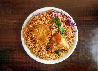 Spicy Chicken pulao with shami kabab onion and cabbage served in plate isolated wooden background...