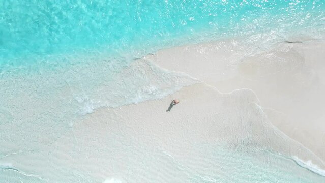 Woman walking on tropical white sand beach with turquoise ocean. Aerial view seascape with female in Maldives
