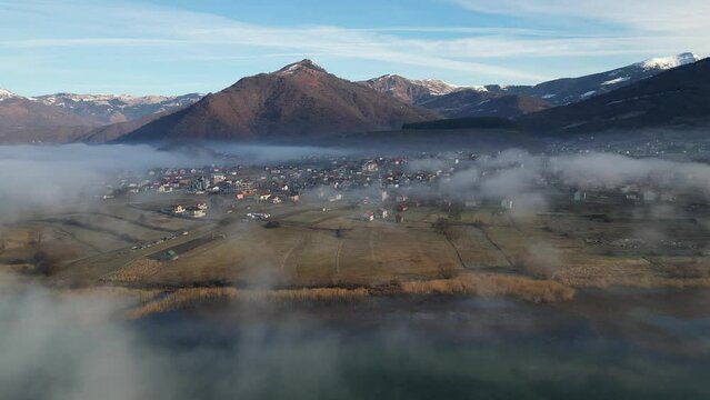 A drone flies over a mountain village covered in morning fog
