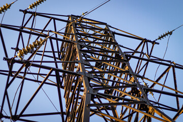 Below, a high voltage power line on a sunny day with a blue sky background, selective focus color photo.