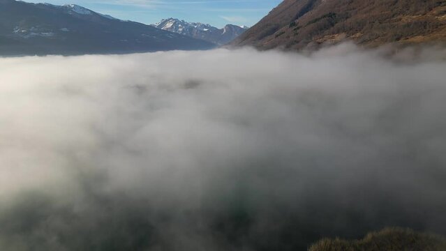 A drone flies over fields and lakes covered with thick morning fog