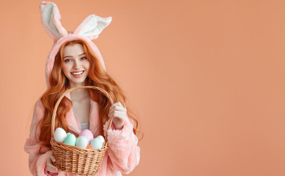 Easter holiday girl in bunny costume holding a live fluffy bunny on beige background