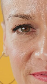 Detailed close-up shot half of a woman's face isolated on yellow background