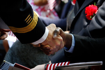 A new United States citizen receives a warm handshake and congratulations during a naturalization...