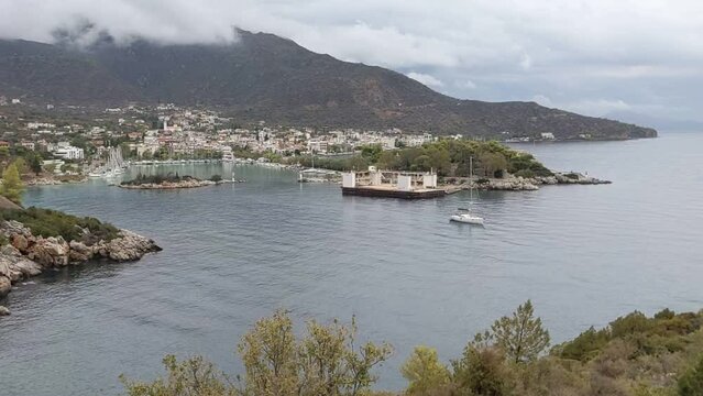 boat departing the marina in methana, greece (sailboat, yacht, catamaran) sea travel (volcanic island peninsula in europe) sailing moving in the bay
