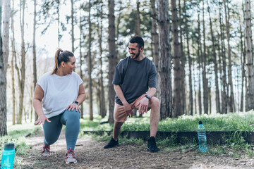 A beautiful, overweight female and her friend enjoy to jogging in the park, then take time to stretch and cool down, savoring the refreshing breeze. - obrazy, fototapety, plakaty