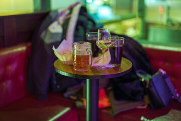 Close-up view of various drinks in glasses on small bar table at bowling center, with blurred...