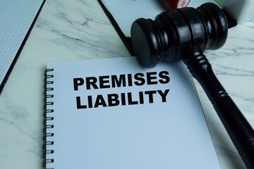 Concept of Premises Liability write on book with gavel isolated on Wooden Table.