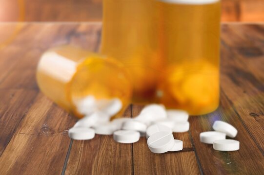 Medical pills spilling from bottle on desk
