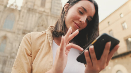 Close up, beautiful traveler girl using looking mobile phone sitting on the steps of an old...