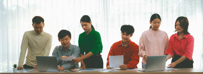 Creative startup group discussion about business plan at meeting room. Successful business people brainstorm marketing idea with document and laptop placed on table. Front view. Variegated.