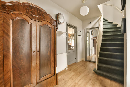 Wooden armoire in hallway with staircase