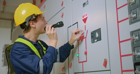 electricians electrical engineer in protective uniform wearing hard hat checking voltage control...