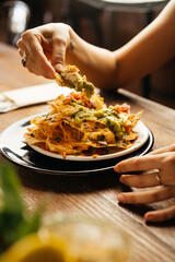 Crop client eating yummy nachos in restaurant - 705230861