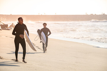 Two surfers run in the beach
