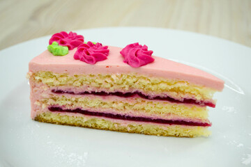 Sweet dessert piece of cake with pink cream and fruit filling with shortbread on a white plate.