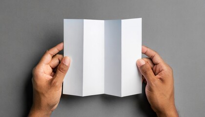 a4 z fold brochure mock up male hands holding a blank tri fold on a gray background - obrazy, fototapety, plakaty