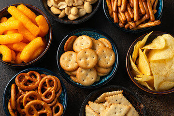 Salty snacks crackers, potato chips, pretzel, peanuts, corn puffs. - obrazy, fototapety, plakaty